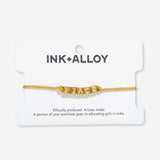 Goldie  - Gold Lurex String Bracelet w/ Block Letters  - Peace